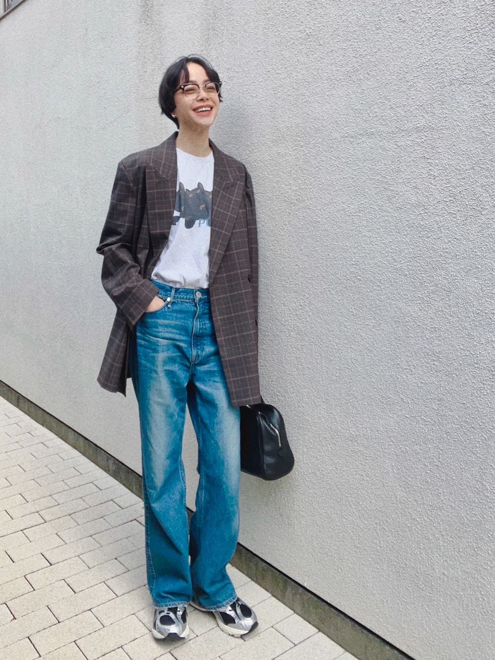 ブラウン系のテーラードジャケット、ブルー系のデニムパンツ、ブラック系のバッグを着用したレディースの秋コーディネートの2枚目の写真