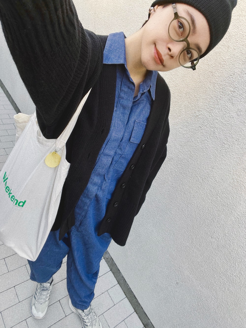 ブラック系のカーディガン/ボレロ、ブルー系のつなぎ/オールインワン、ホワイト系のスニーカーを着用したレディースの冬コーディネートの2枚目の写真