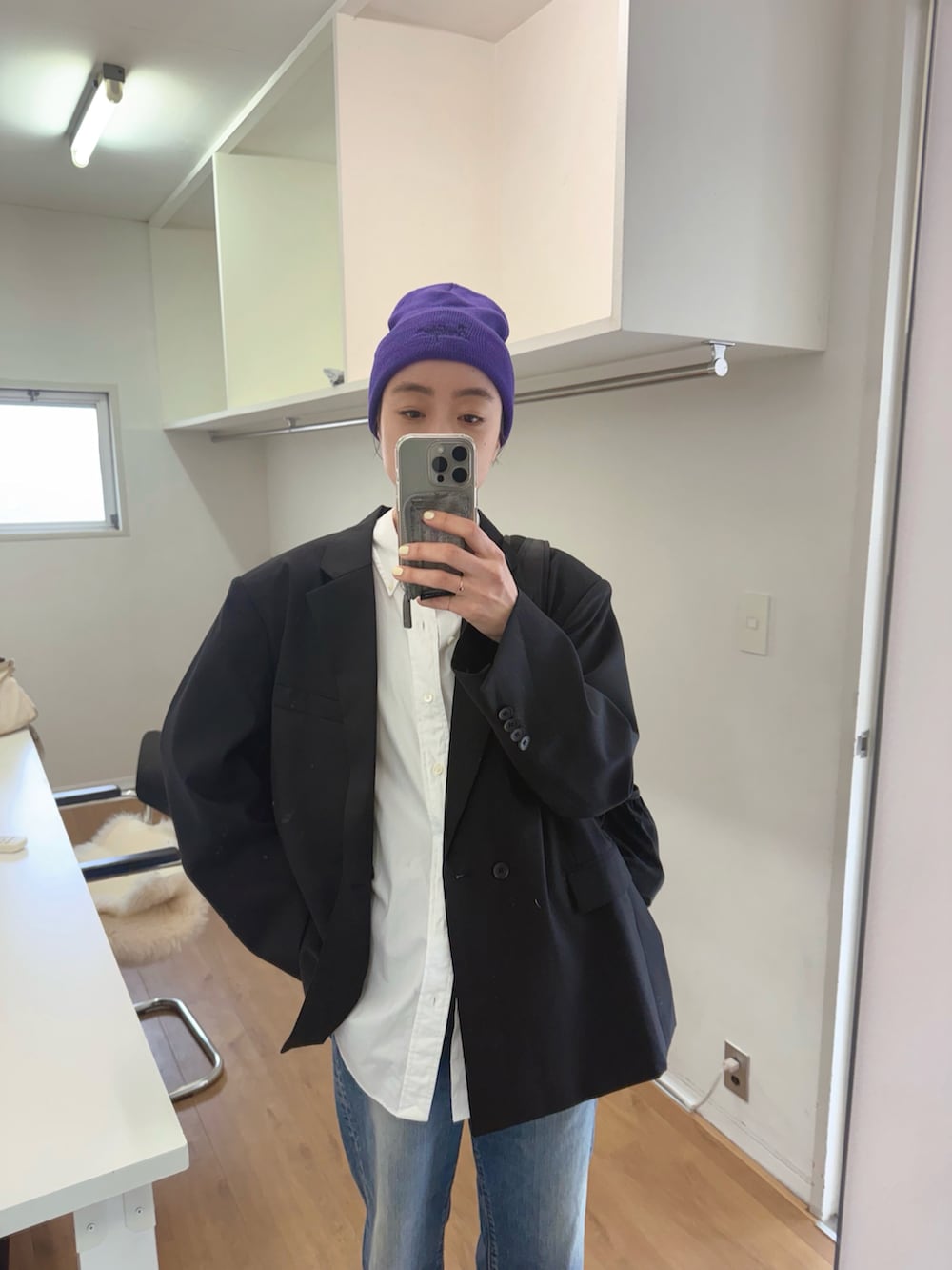 ブラック系のテーラードジャケット、ブラック系のバックパック/リュック、ブルー系のデニムパンツを着用したレディースの春コーディネートの2枚目の写真