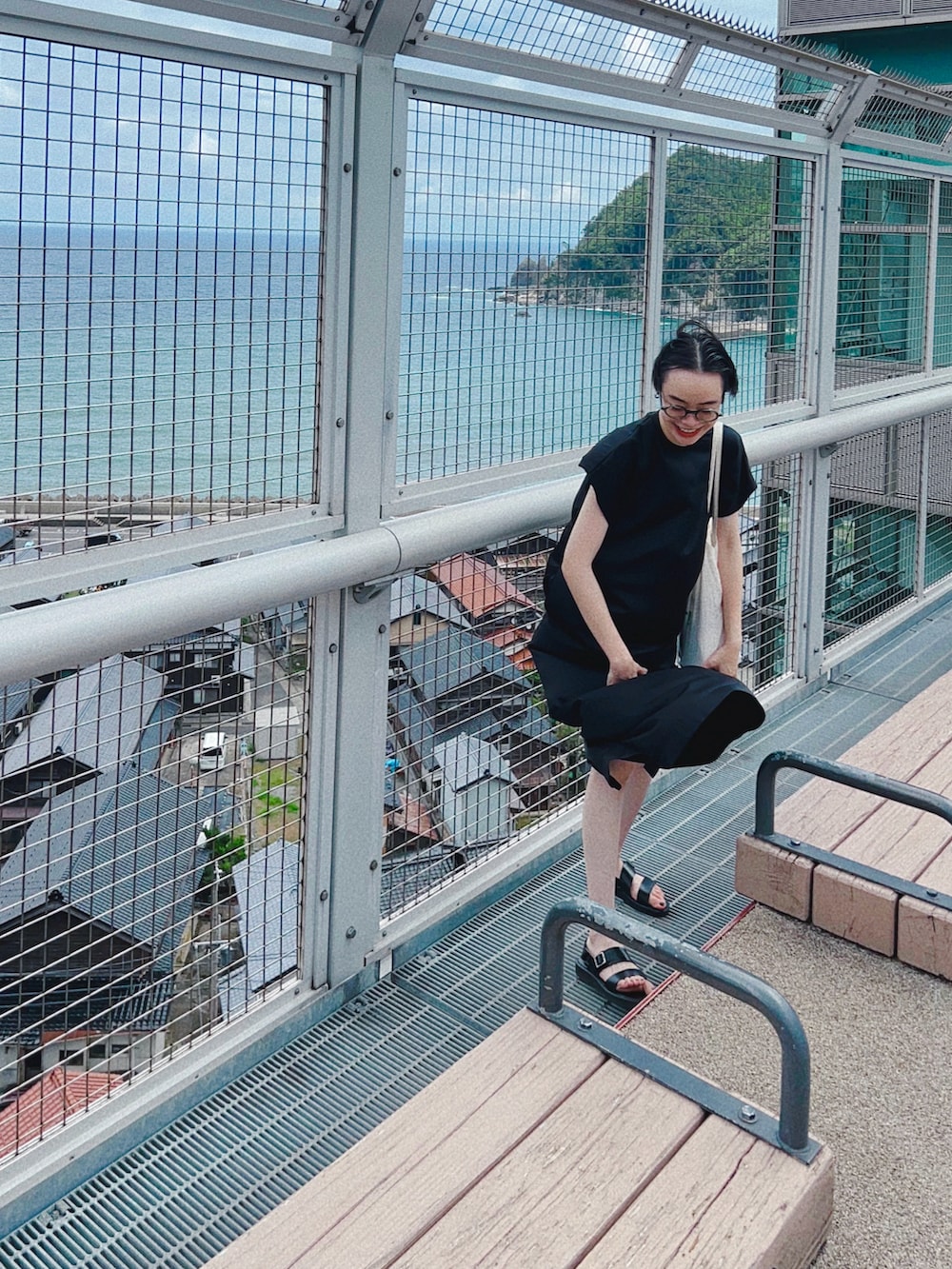 ブラック系のワンピース、ブラック系のサンダルを着用したレディースの夏コーディネートの2枚目の写真