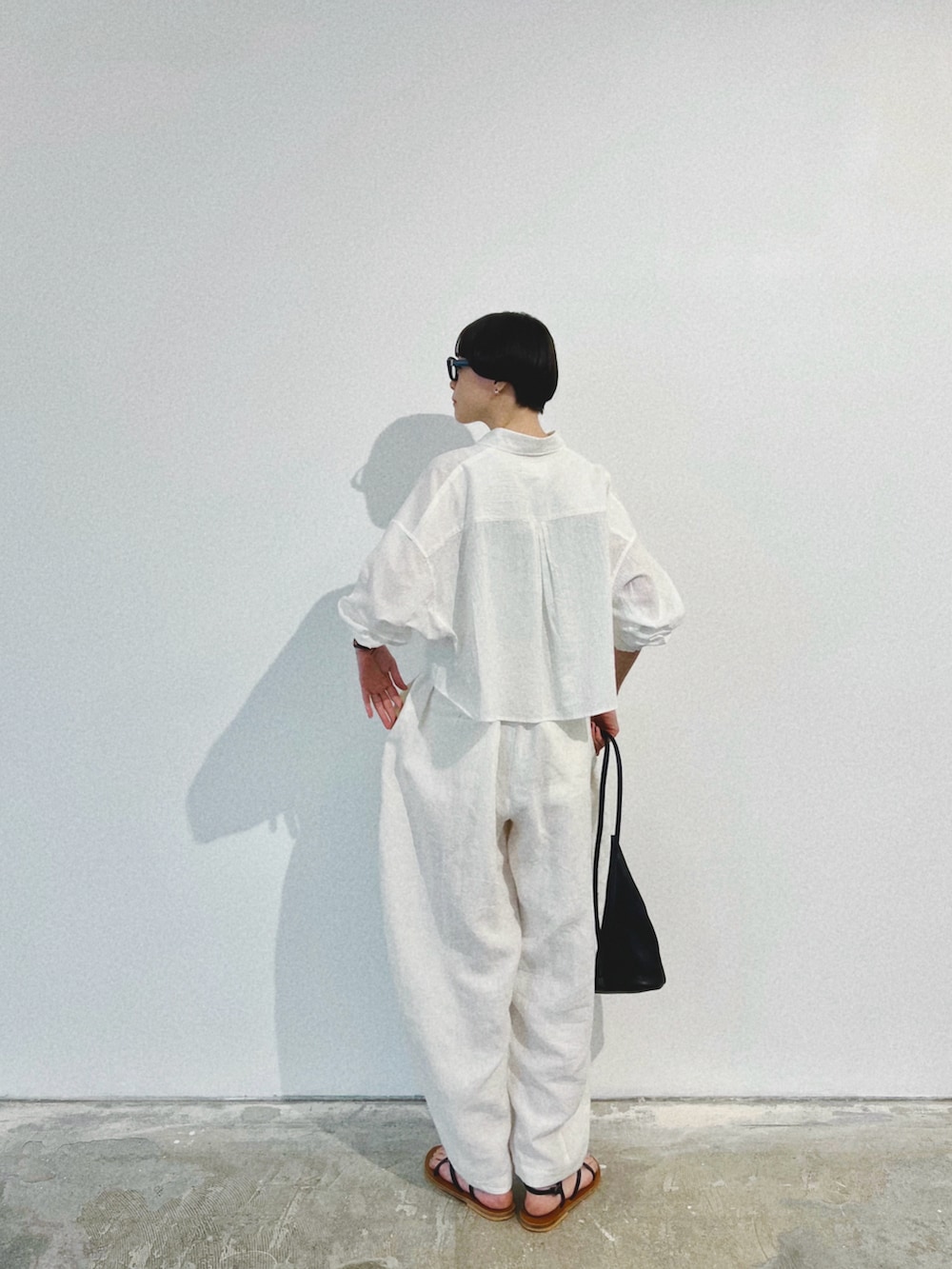 ホワイト系のシャツ/ブラウス、ホワイト系のパンツ、ブラック系のバッグを着用したレディースの夏コーディネートの4枚目の写真