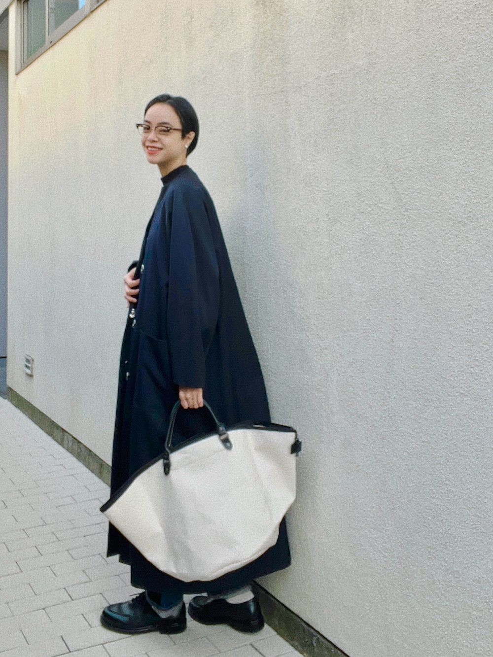 ブルー系のジャケット/アウター、ブラック系のニット/セーター、ホワイト系のバッグを着用したレディースの冬コーディネートの2枚目の写真