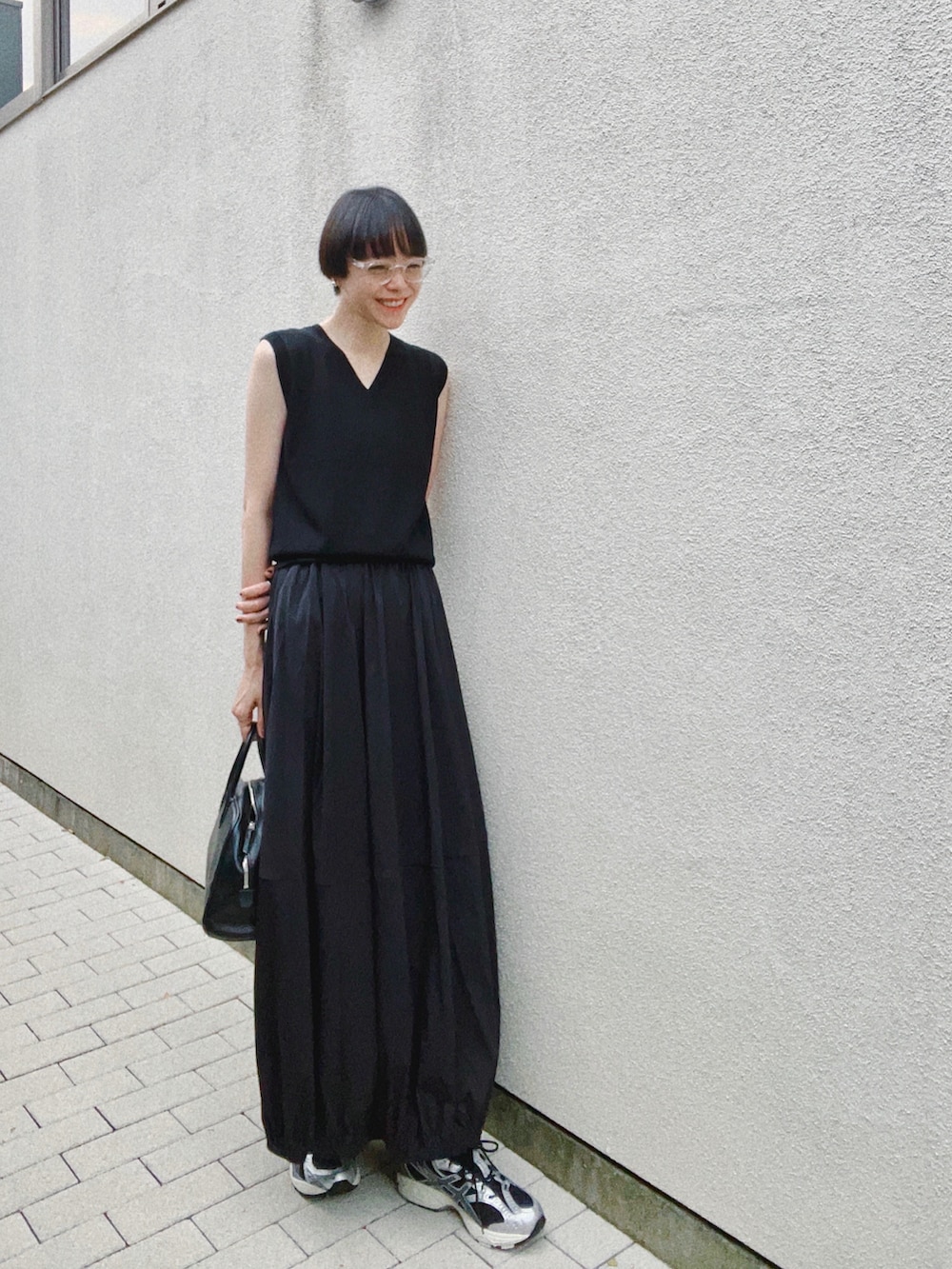 ブラック系のスニーカー、ブラック系のスカート、ブラック系のバッグを着用したレディースの秋コーディネートの2枚目の写真