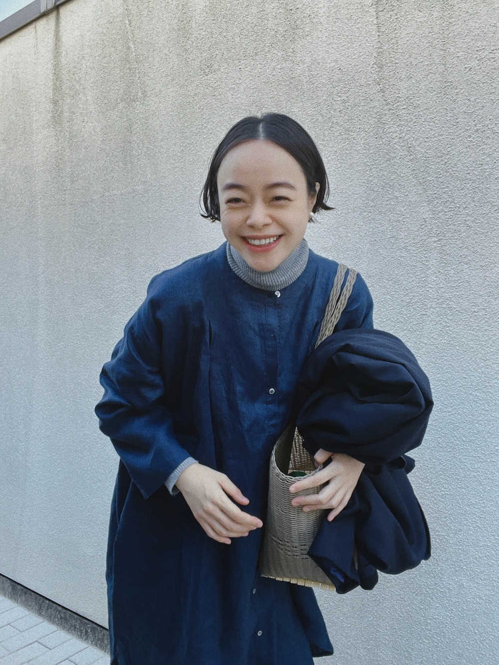 ブルー系のシャツ/ブラウス、グレー系のニット/セーター、ベージュ系のかごバッグを着用したレディースの冬コーディネートの3枚目の写真