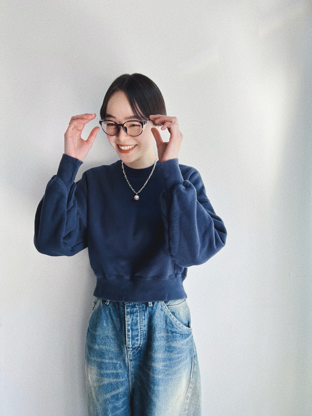 ブルー系のデニムパンツ、ブルー系のスウェット、ブラック系のバッグを着用したレディースの春コーディネートの2枚目の写真