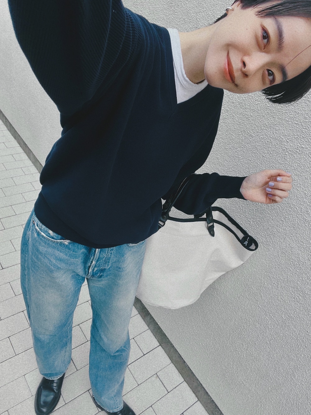 ブルー系のデニムパンツ、ブルー系のニット/セーター、ホワイト系のTシャツ/カットソーを着用したレディースの春コーディネートの3枚目の写真