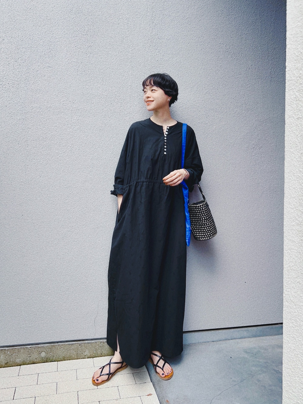 ブラック系のワンピース/ドレス、ブラック系のバッグ、ブルー系のトートバッグを着用したレディースの夏コーディネートの2枚目の写真