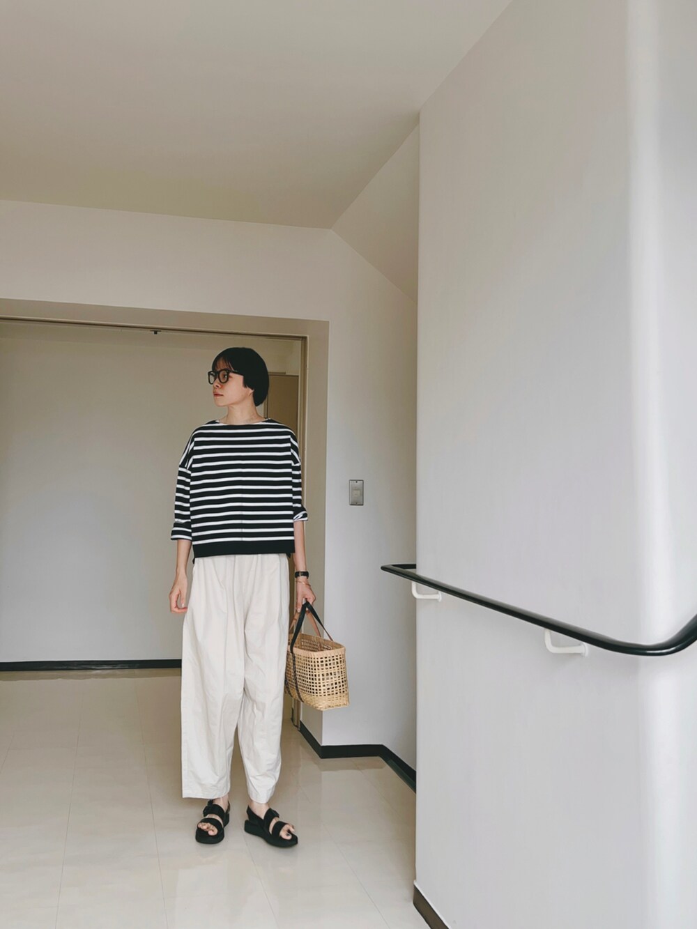 ブラック系のトップス、ホワイト系のその他パンツ、ブラック系のサンダルを着用したレディースの夏コーディネートの2枚目の写真