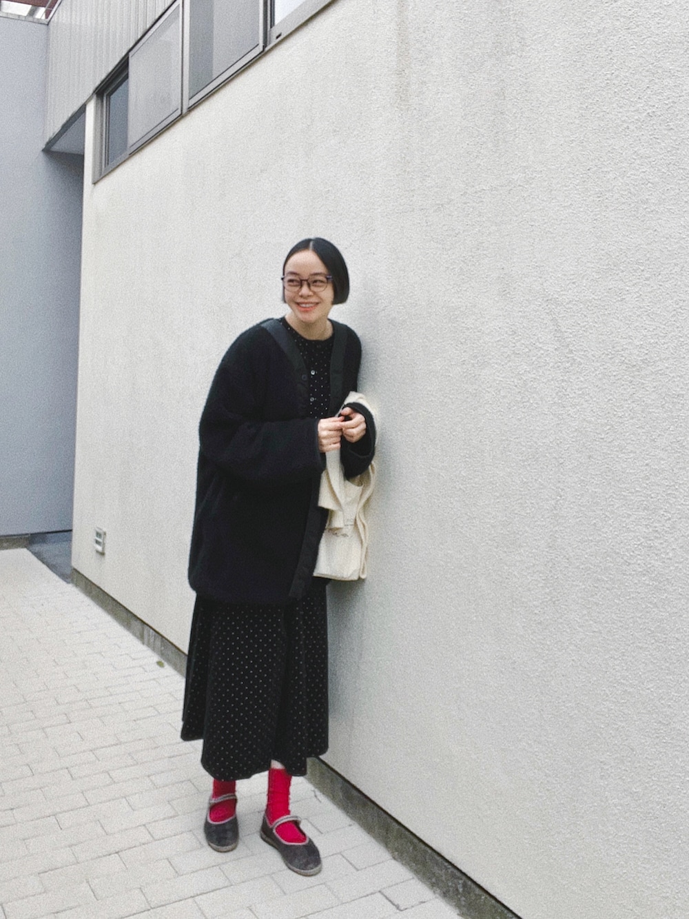 ブラック系のノーカラージャケット、ブラック系のワンピース、グレー系のシューズを着用したレディースの春コーディネートの2枚目の写真