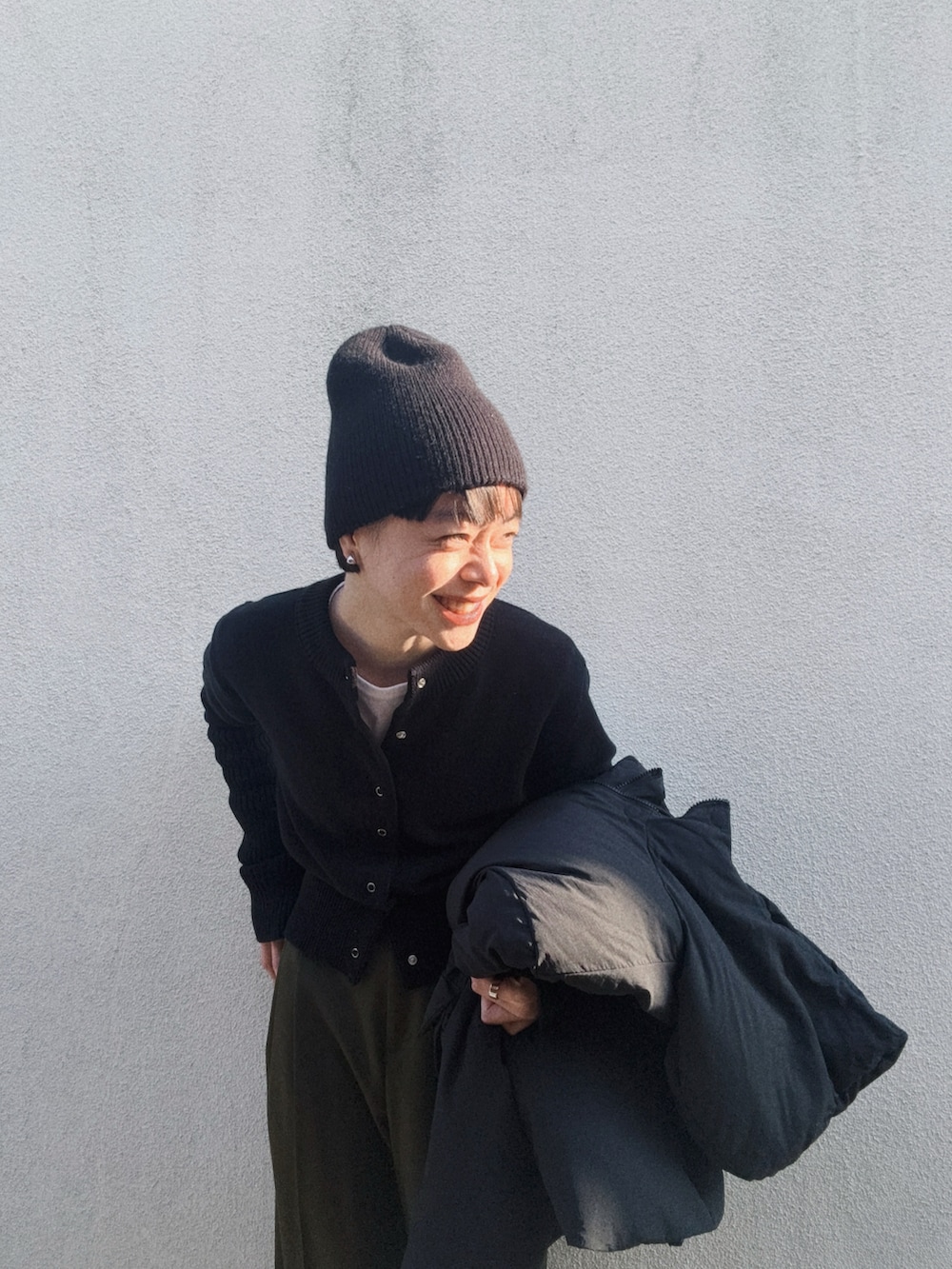 ブラック系のカーディガン/ボレロ、グリーン系のスラックス、グレー系のスニーカーを着用したレディースの春コーディネートの3枚目の写真