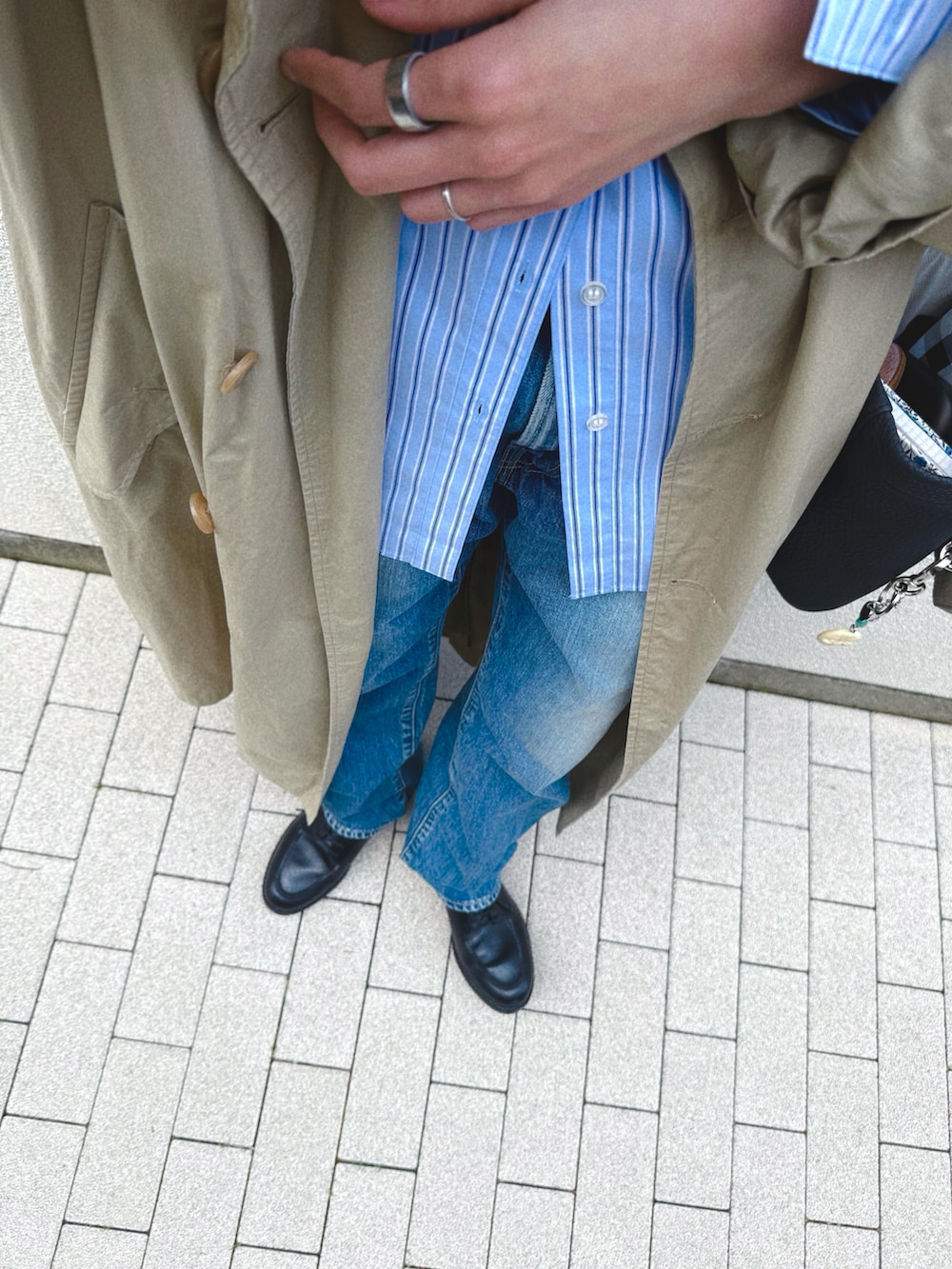 ブラック系のドレスシューズ、ブルー系のデニムパンツ、ベージュ系のトレンチコートを着用したレディースの春コーディネートの3枚目の写真