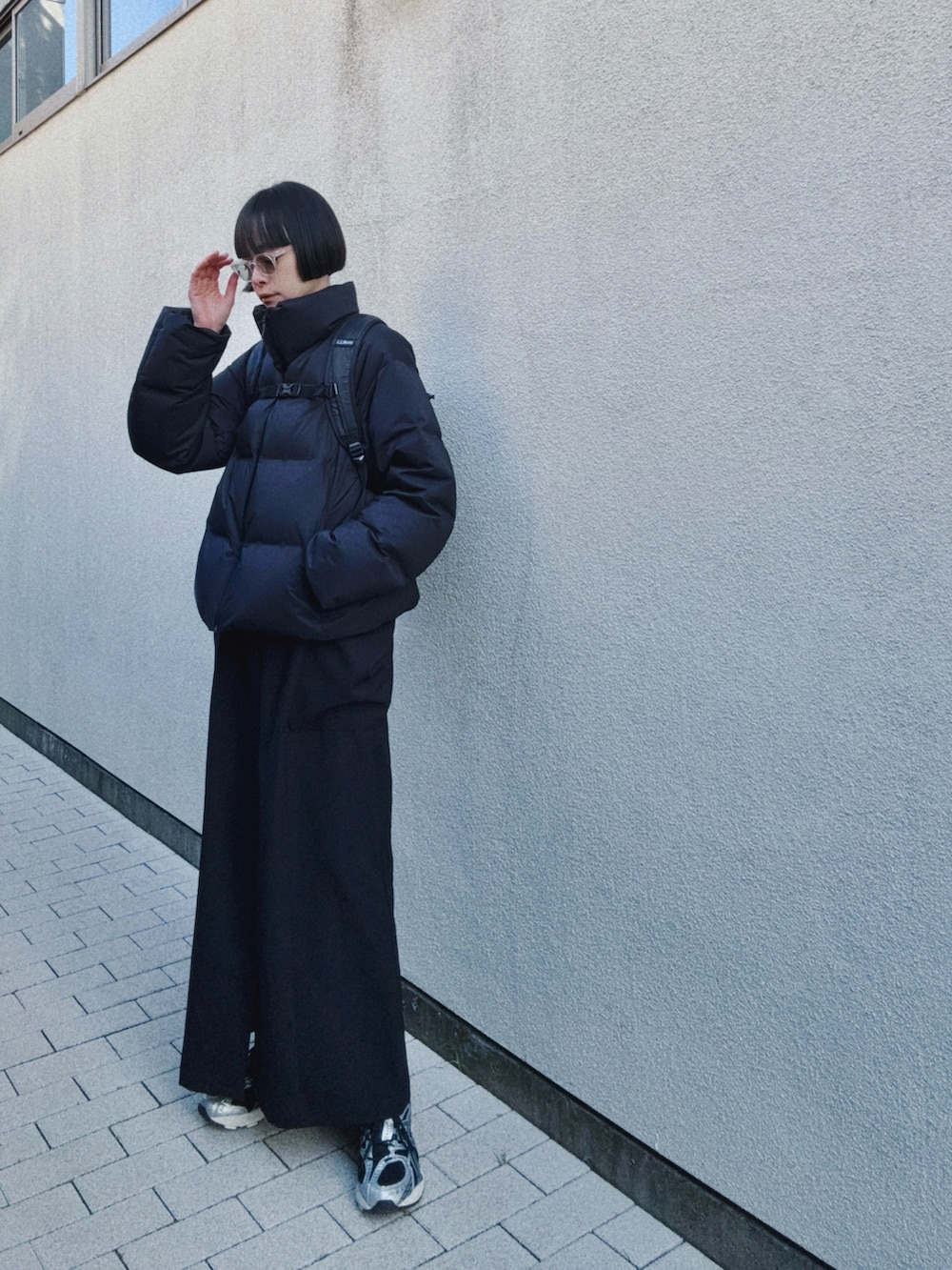 ブラック系のバックパック/リュック、ブラック系のドレス、ブラック系のスニーカーを着用したレディースの冬コーディネートの2枚目の写真