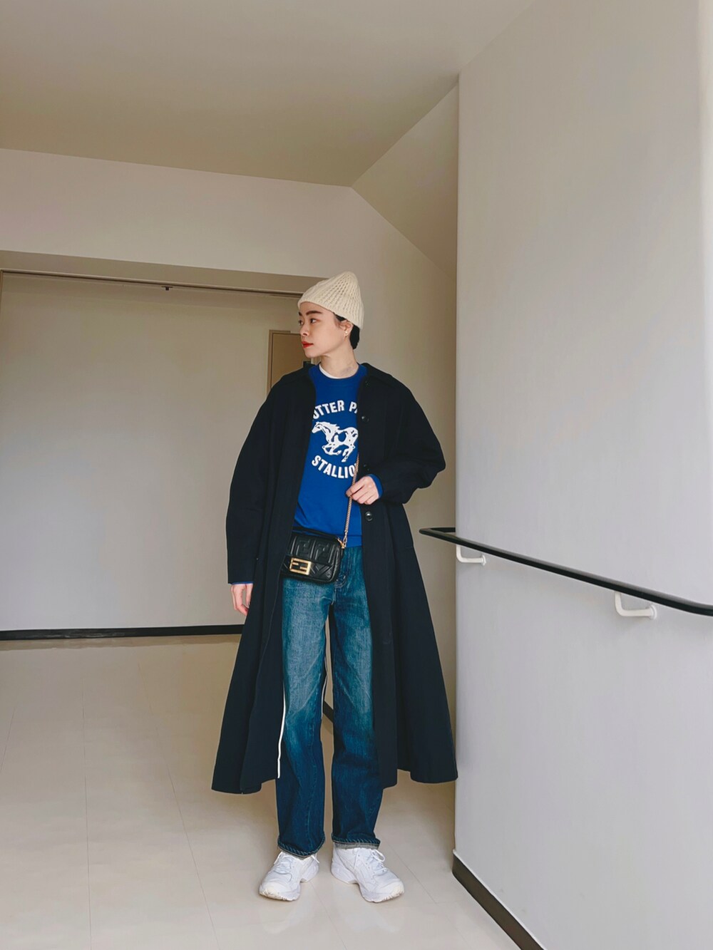 ブルー系のスウェット、ブルー系のデニムパンツ、ブルー系のステンカラーコートを着用したレディースの冬コーディネートの2枚目の写真