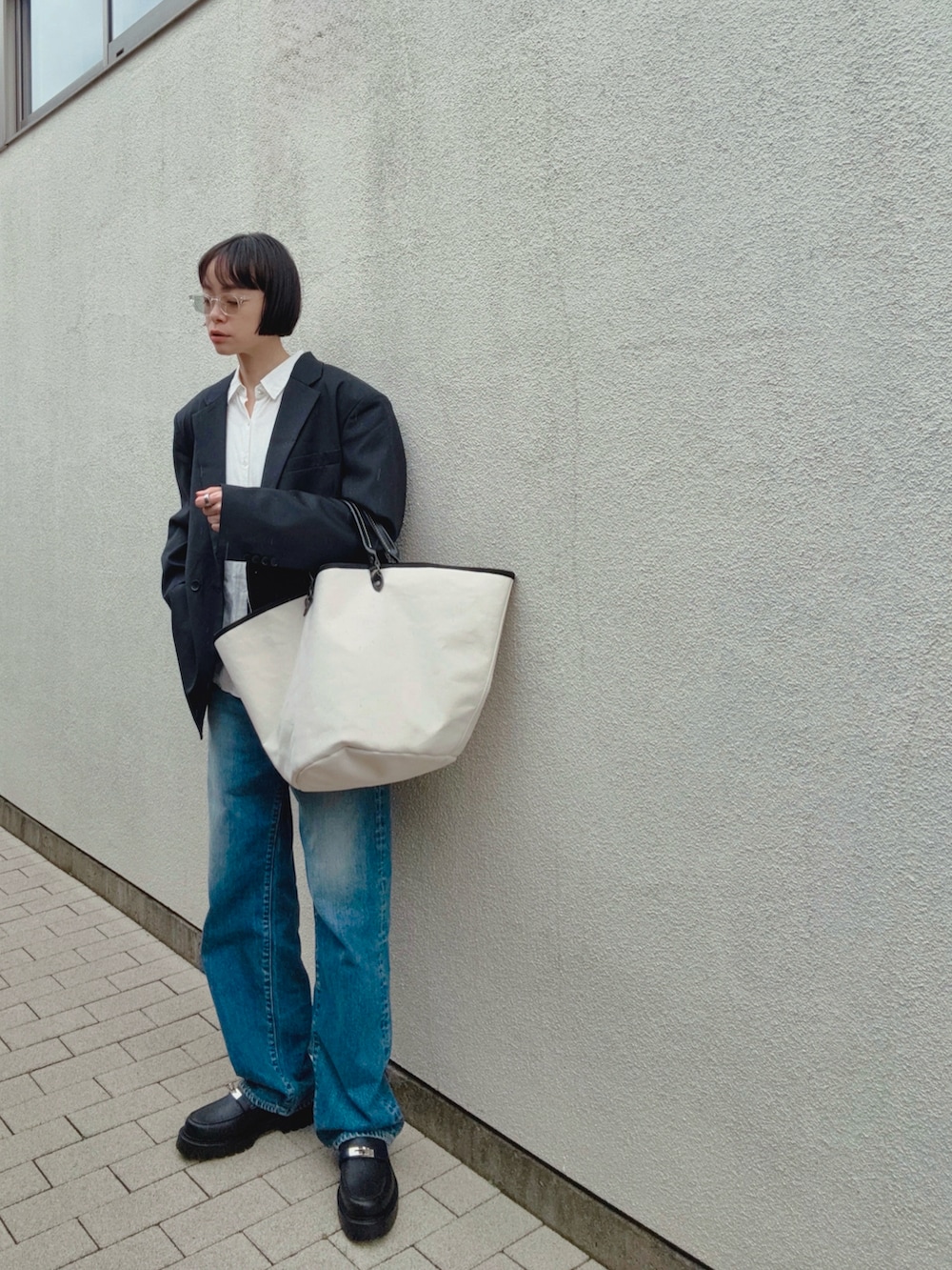 ブラック系のローファー、ブルー系のデニムパンツ、ホワイト系のバッグを着用したレディースの春コーディネートの2枚目の写真