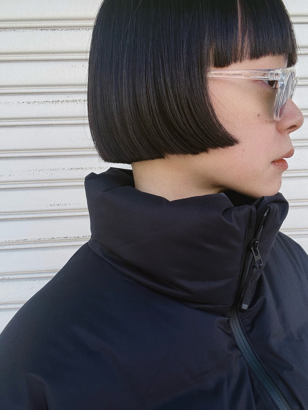 ブラック系のドレス、パープル系のバッグ、ブラック系のダウンジャケット/コートを着用したレディースの冬コーディネートの2枚目の写真