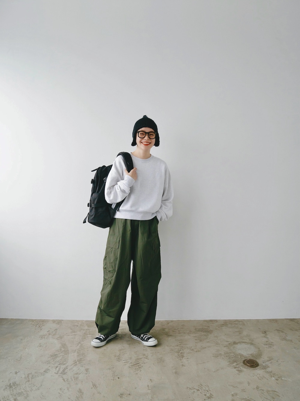 グレー系のスウェット、ブラック系のバックパック/リュック、グリーン系のカーゴパンツを着用したレディースの冬コーディネートの2枚目の写真