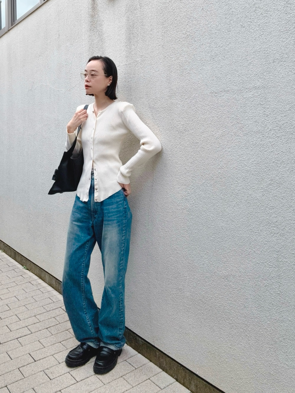 ブルー系のデニムパンツ、ホワイト系のカーディガン/ボレロ、ブラック系のバッグを着用したレディースの秋コーディネートの2枚目の写真