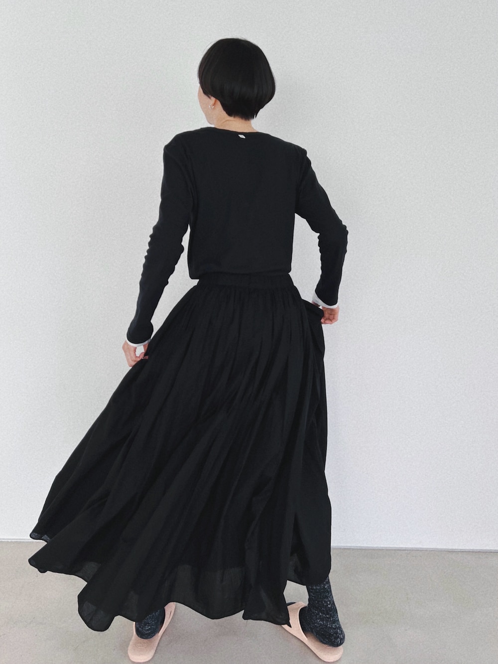 ブラック系のスカート、ブラック系のTシャツ/カットソー、ホワイト系のTシャツ/カットソーを着用したレディースの春コーディネートの2枚目の写真