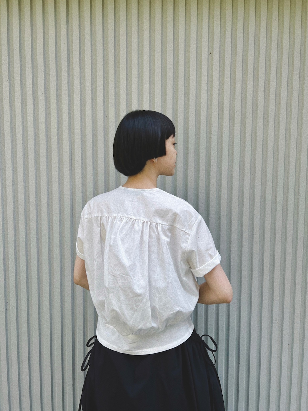 ホワイト系のシャツ/ブラウス、ブラック系のスカート、ブラック系のショルダーバッグを着用したレディースの春コーディネートの3枚目の写真