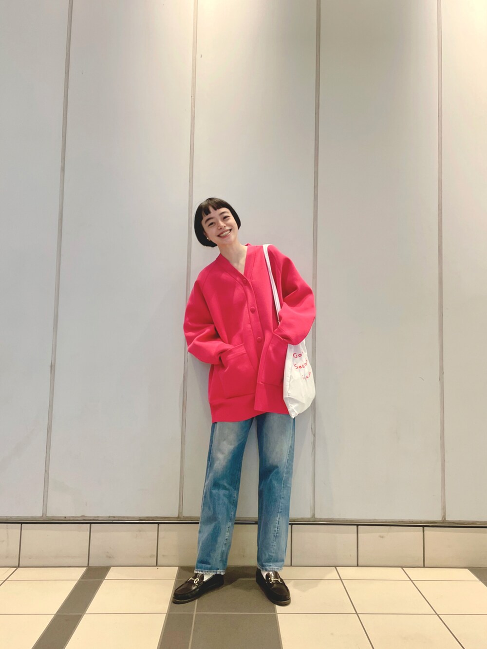 ピンク系のカーディガン/ボレロ、ホワイト系のトートバッグ、ブルー系のデニムパンツを着用したレディースの秋コーディネートの2枚目の写真