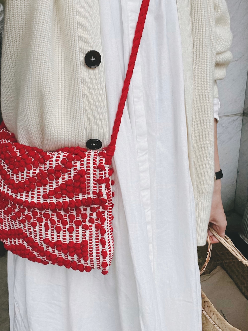 レッド系のバッグ、ホワイト系のカーディガン/ボレロ、ホワイト系のワンピースを着用したレディースの秋コーディネートの2枚目の写真