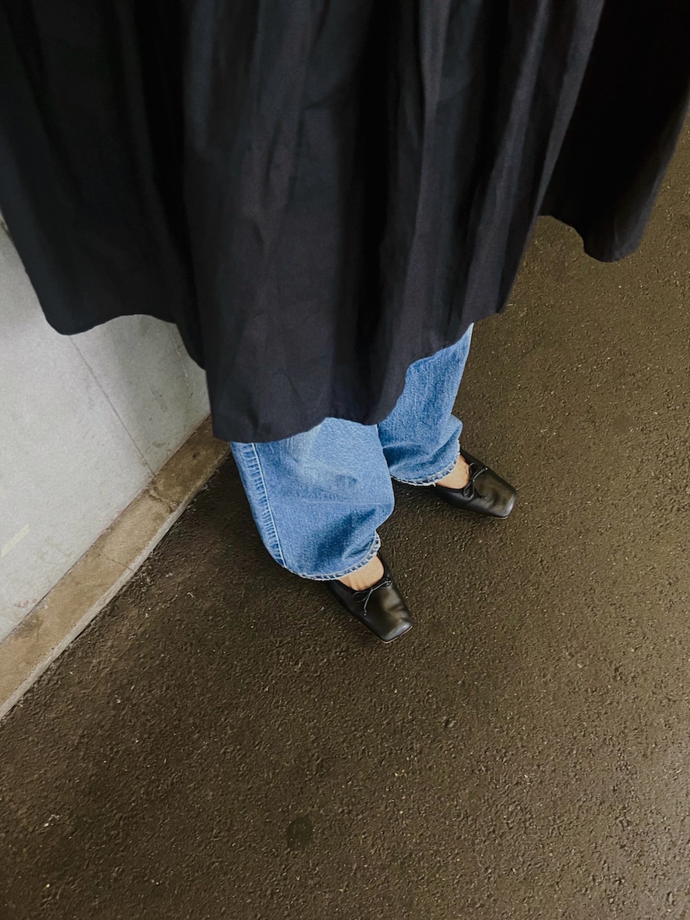 ブラック系のワンピース、ブルー系のデニムパンツ、ブラック系のバレエシューズを着用したレディースの秋コーディネートの2枚目の写真