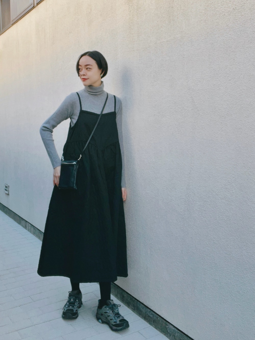 グレー系のニット/セーター、ブラック系のワンピース/ドレス、グレー系のスニーカーを着用したレディースの冬コーディネートの2枚目の写真