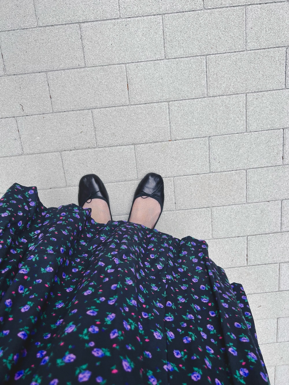 ブラック系のワンピース、ブラック系のバレエシューズ、ブルー系のキャップを着用したレディースの春コーディネートの2枚目の写真