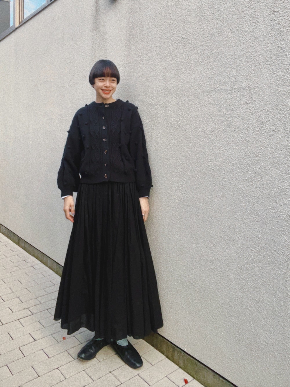ブラック系のカーディガン/ボレロ、ブラック系のスカート、ブラック系のバレエシューズを着用したレディースの秋コーディネートの2枚目の写真