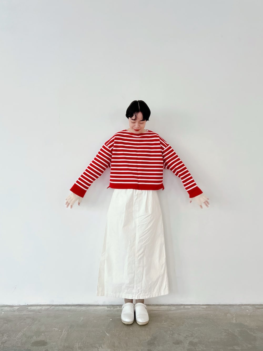 レッド系のトップス、ホワイト系のスカート、ホワイト系のシューケア用品を着用したレディースの冬コーディネートの2枚目の写真