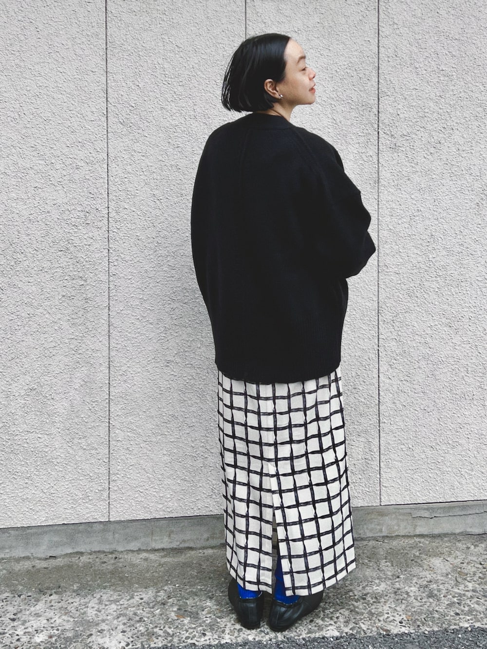 ブラック系のカーディガン/ボレロ、ベージュ系のスカート、ブラック系のバレエシューズを着用したレディースの春コーディネートの2枚目の写真