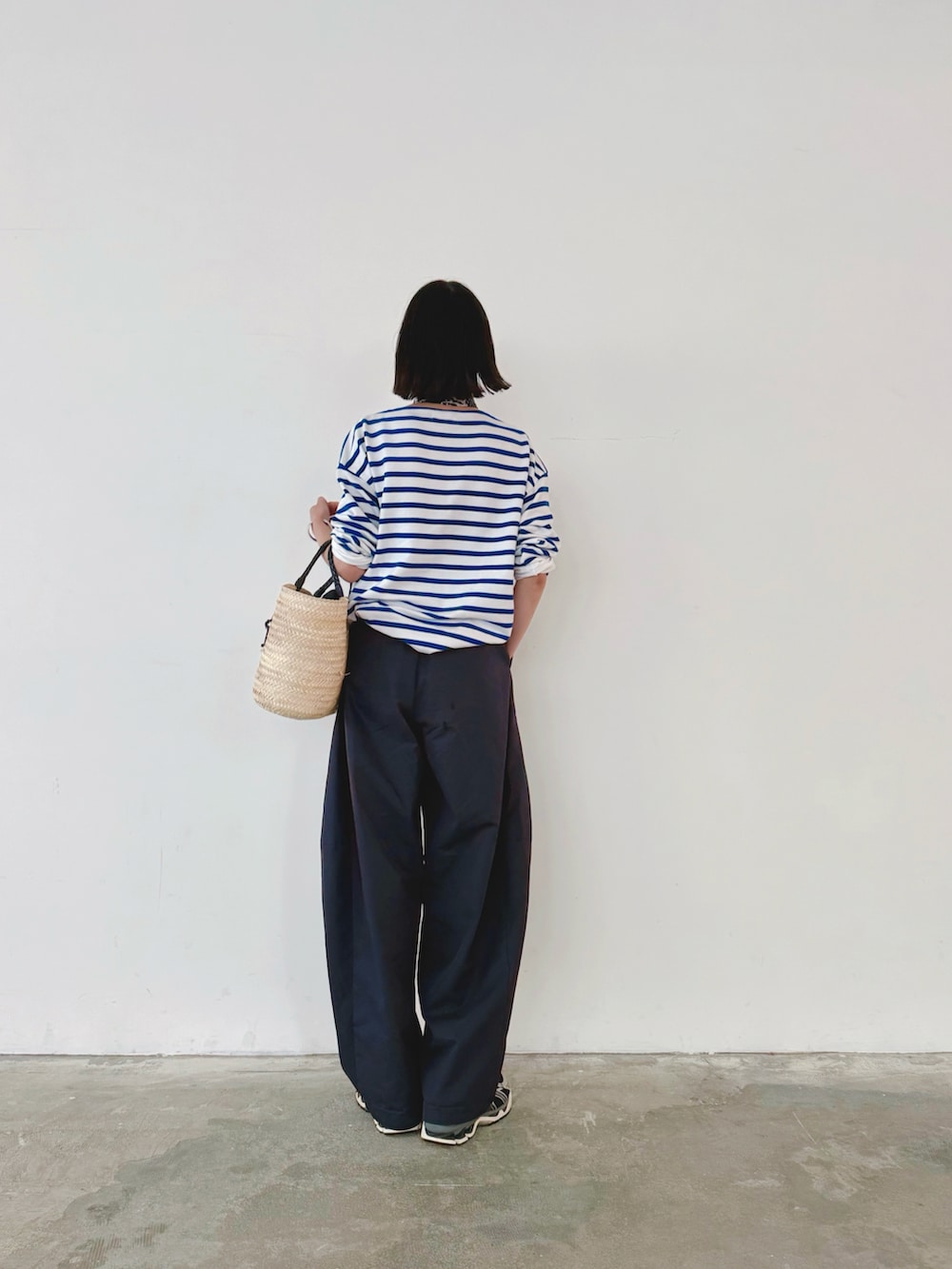 ブルー系のその他パンツ、ブルー系のTシャツ/カットソー、ベージュ系のかごバッグを着用したレディースの秋コーディネートの2枚目の写真