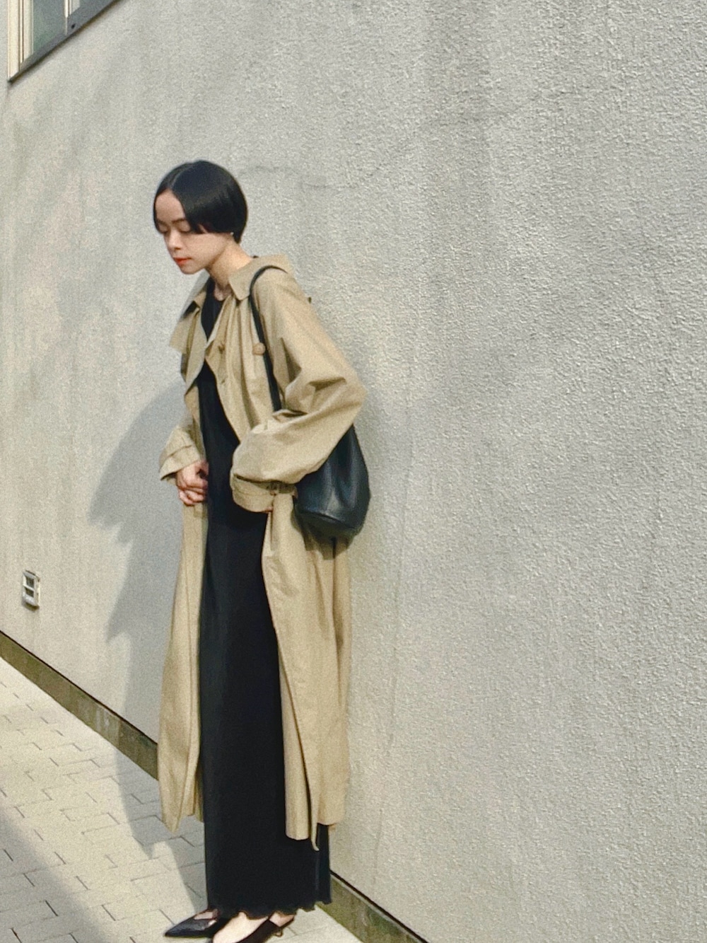 ブラック系のパンプス、ベージュ系のトレンチコート、ブラック系のワンピースを着用したレディースの春コーディネートの2枚目の写真