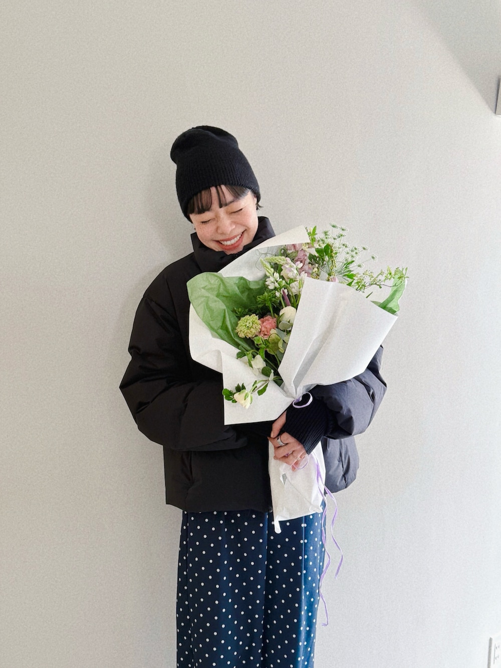 ブルー系のスカート、ブラック系のダウンジャケット/コート、ブラック系のスリッポンを着用したレディースの冬コーディネートの2枚目の写真