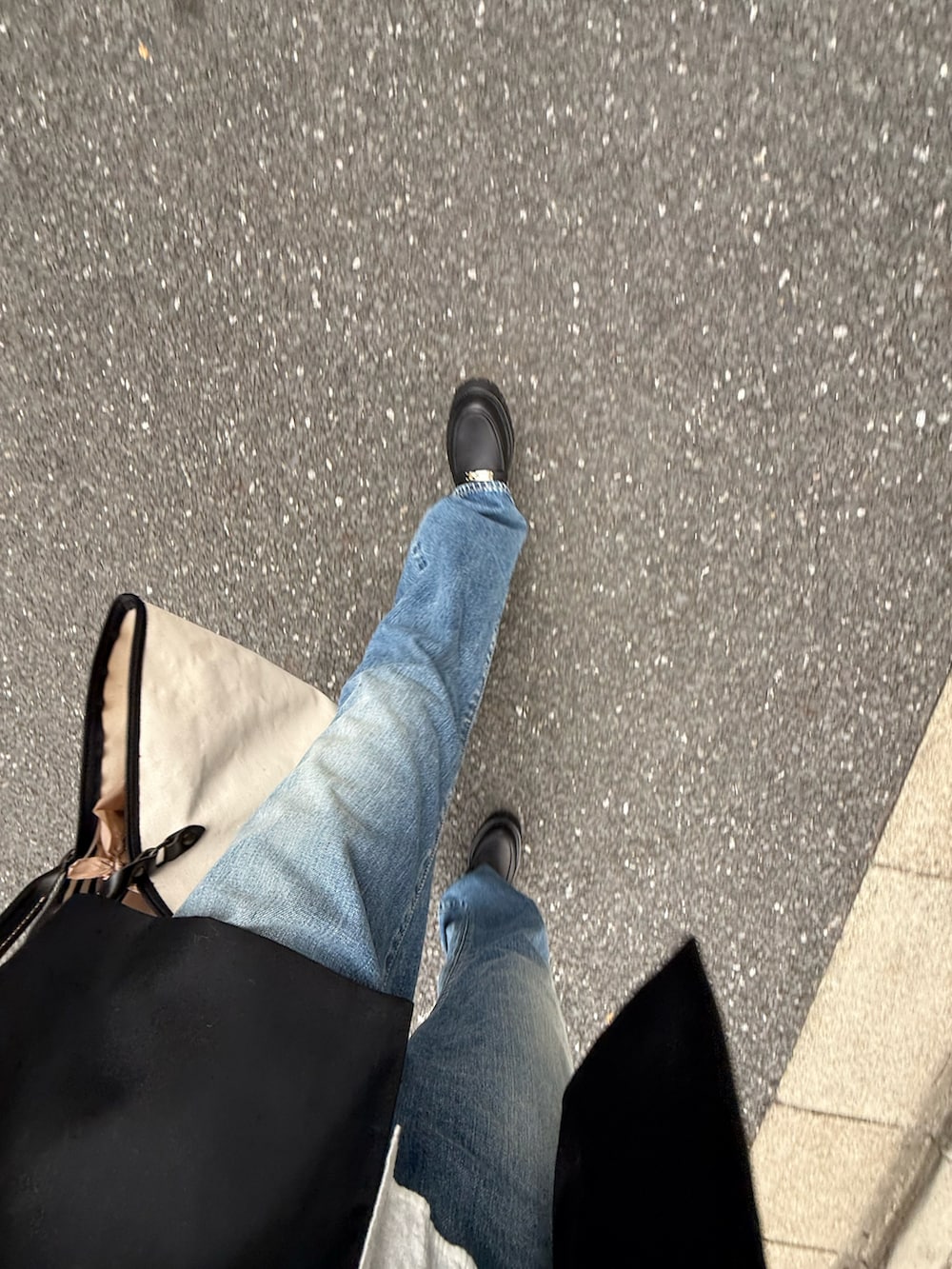 ブラック系のローファー、ブルー系のデニムパンツ、ホワイト系のバッグを着用したレディースの春コーディネートの3枚目の写真