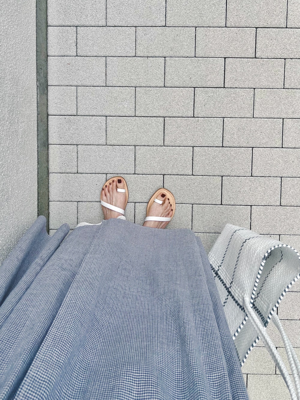 ブルー系のワンピース、ホワイト系のスカート、ホワイト系のサンダルを着用したレディースの春コーディネートの5枚目の写真