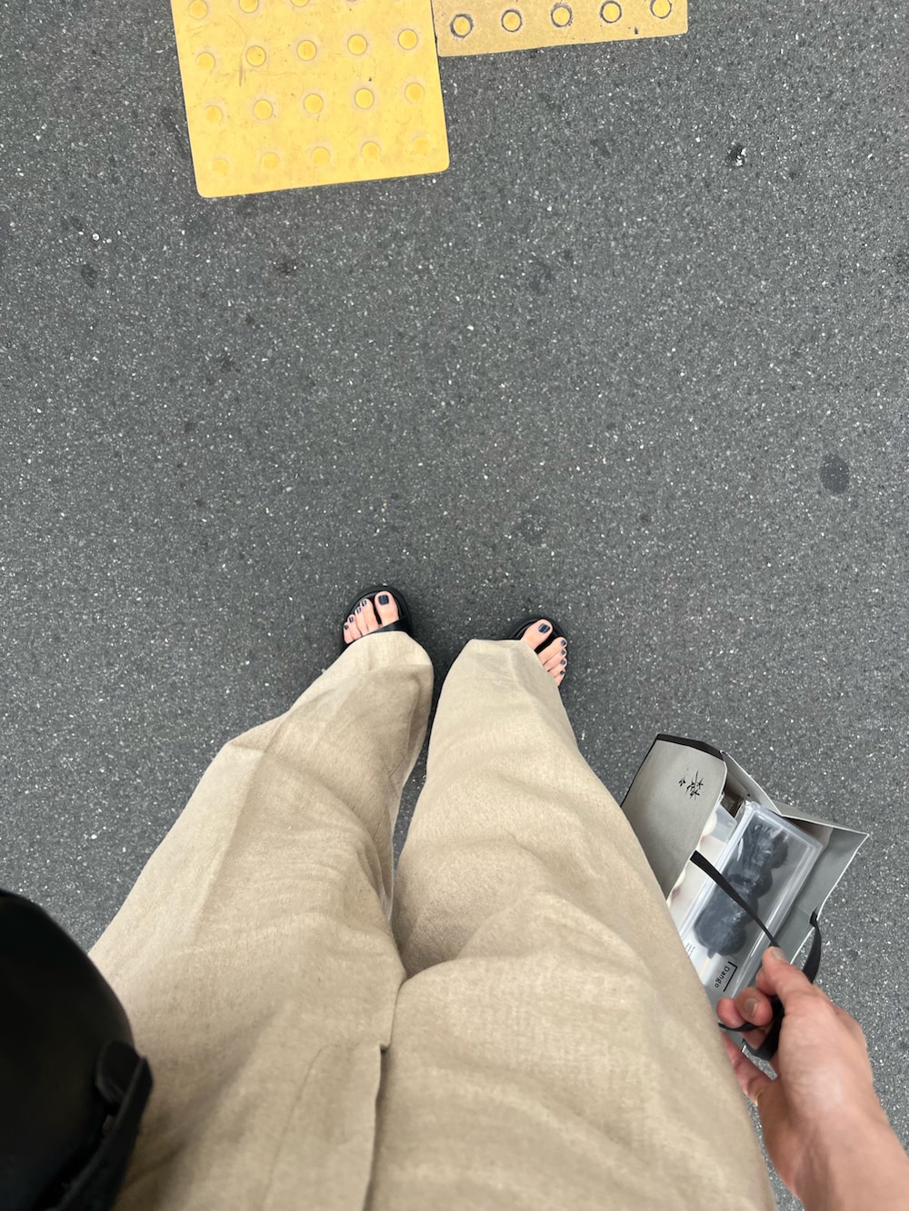 ブラック系のバッグ、ホワイト系のシャツ/ブラウス、ベージュ系のパンツを着用したレディースの夏コーディネートの3枚目の写真