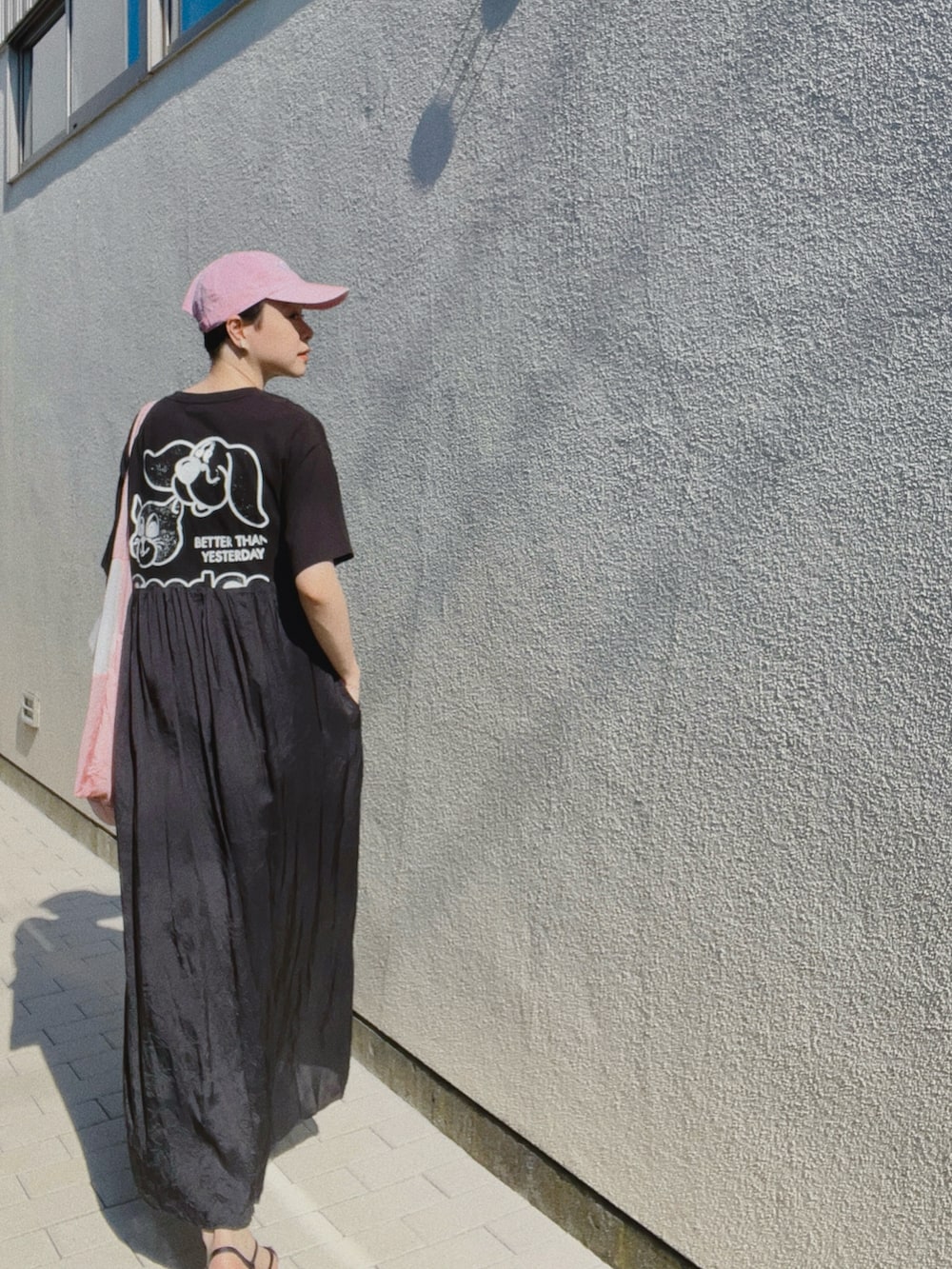 ブラック系のワンピース/ドレス、ブラック系のサンダル、ピンク系のキャップを着用したレディースの夏コーディネートの2枚目の写真