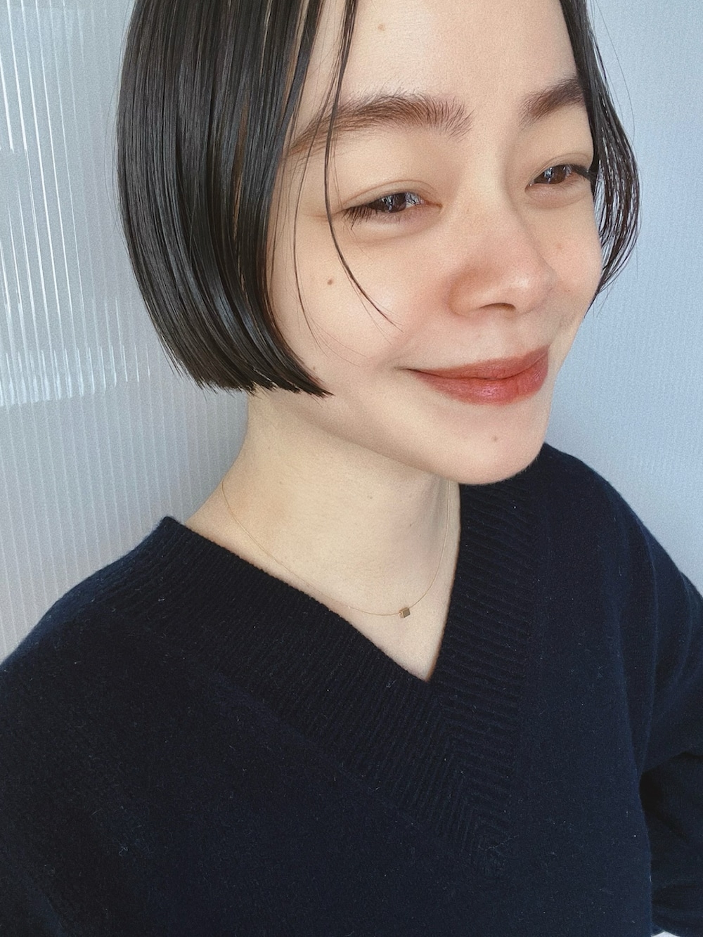 ブラック系のパンツ、ホワイト系のジャケット/アウター、ブルー系のニット/セーターを着用したレディースの冬コーディネートの2枚目の写真