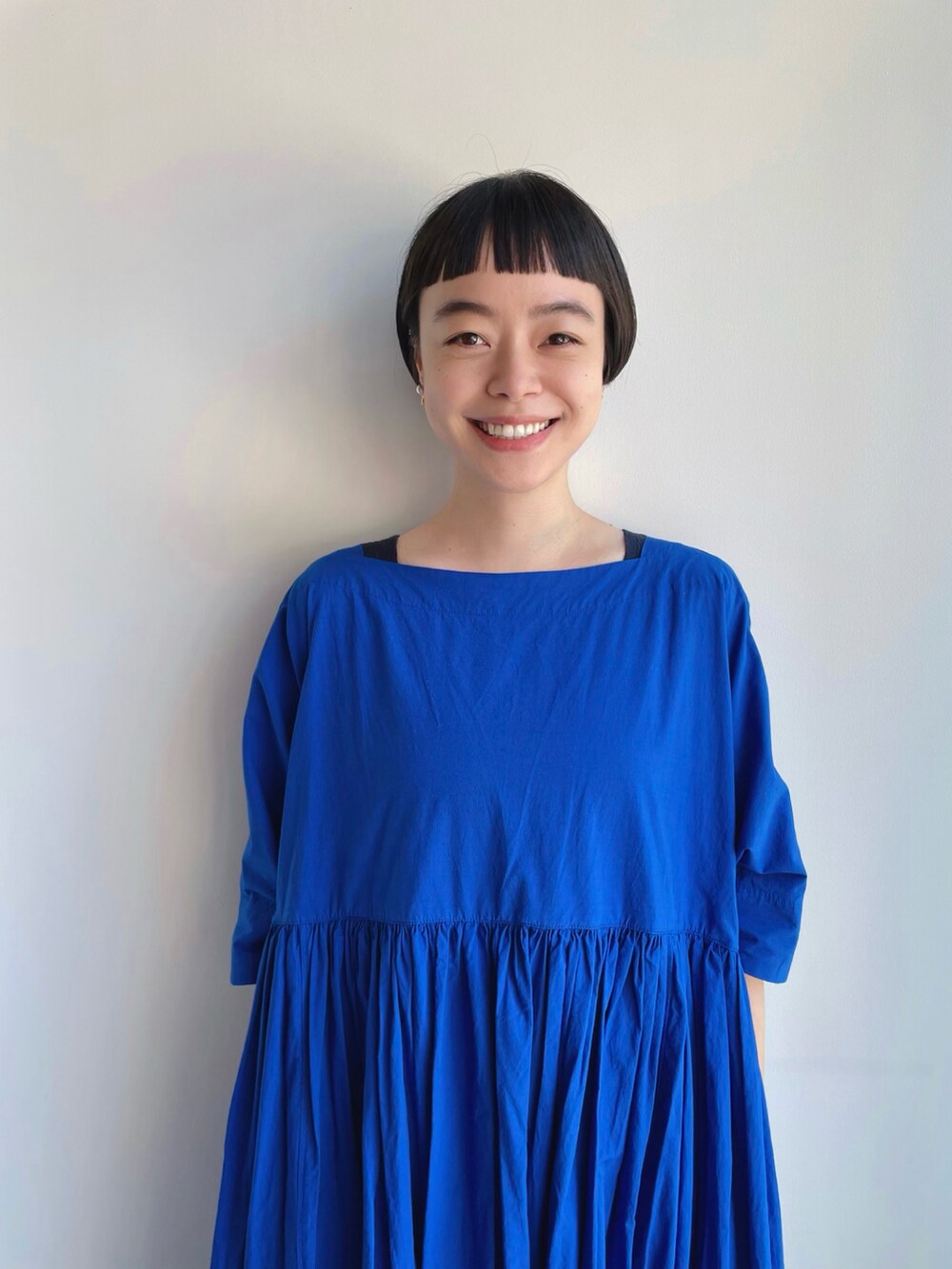 ブラック系のかごバッグ、ブルー系のワンピース、グリーン系のイヤリングを着用したレディースの夏コーディネートの2枚目の写真