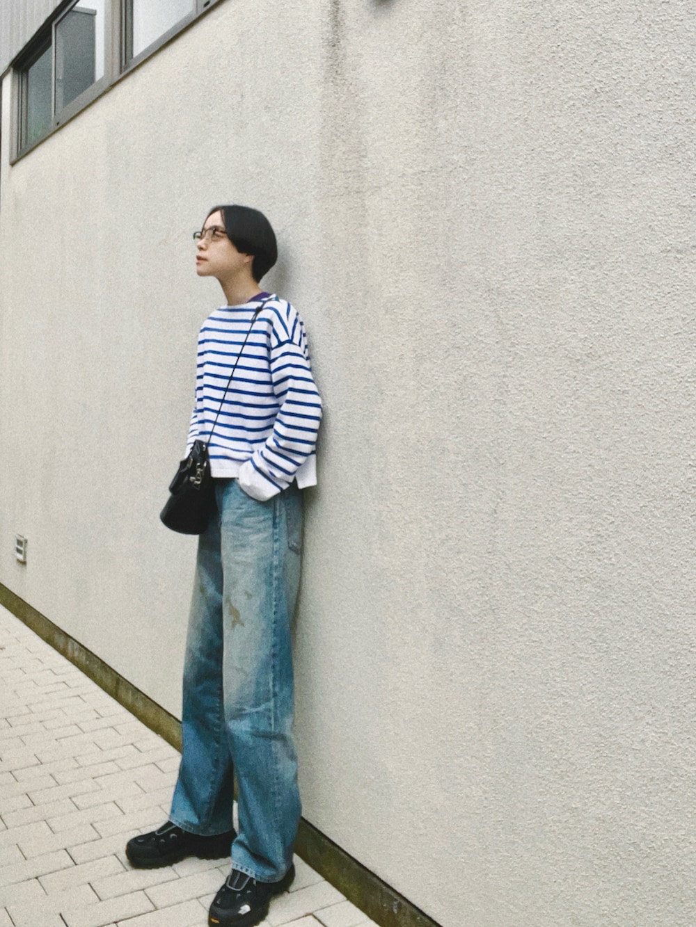 ブルー系のデニムパンツ、ブルー系のトップス、ブラック系のショルダーバッグを着用したレディースの春コーディネートの2枚目の写真