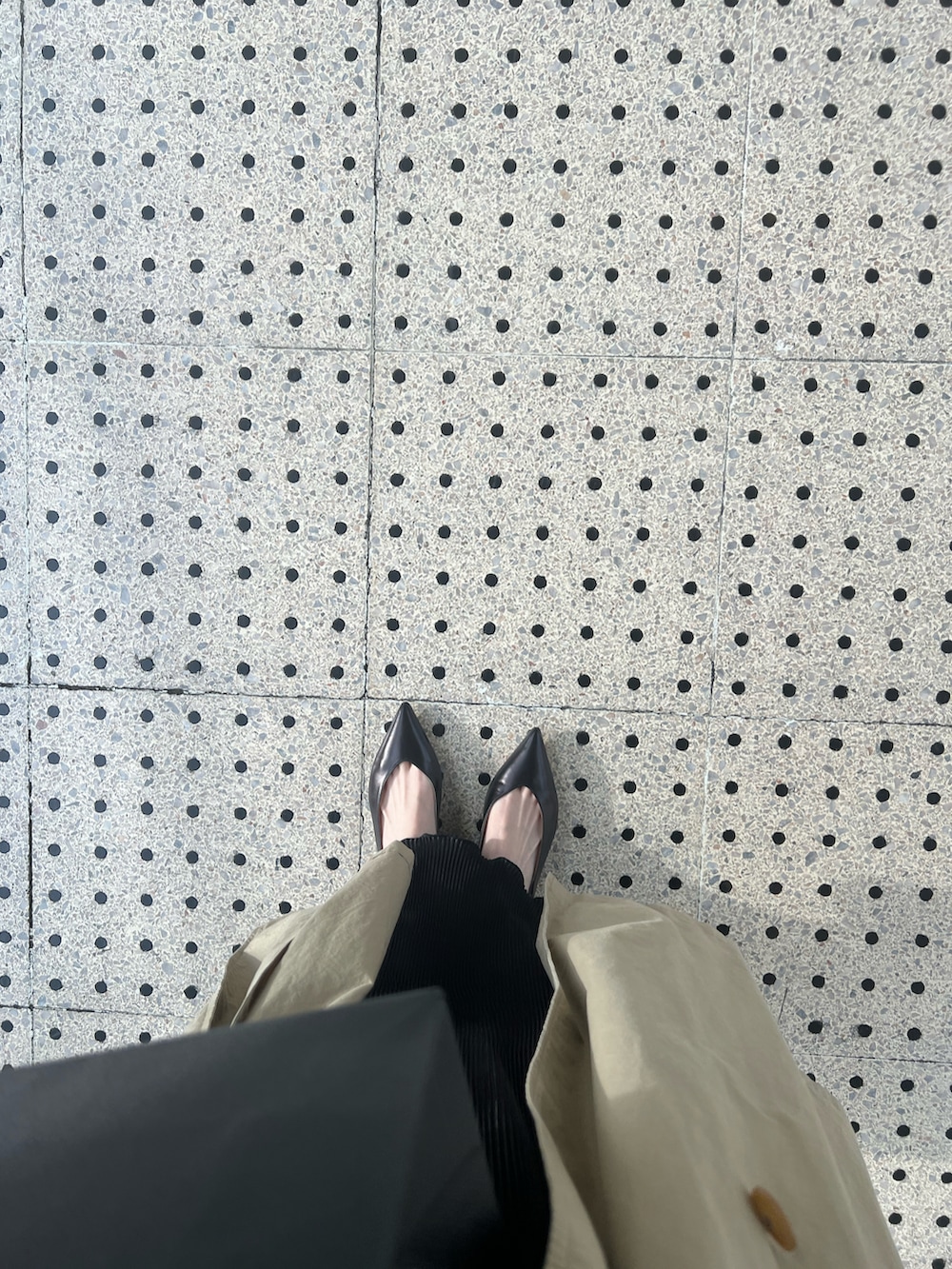 ブラック系のパンプス、ベージュ系のトレンチコート、ブラック系のワンピースを着用したレディースの春コーディネートの3枚目の写真