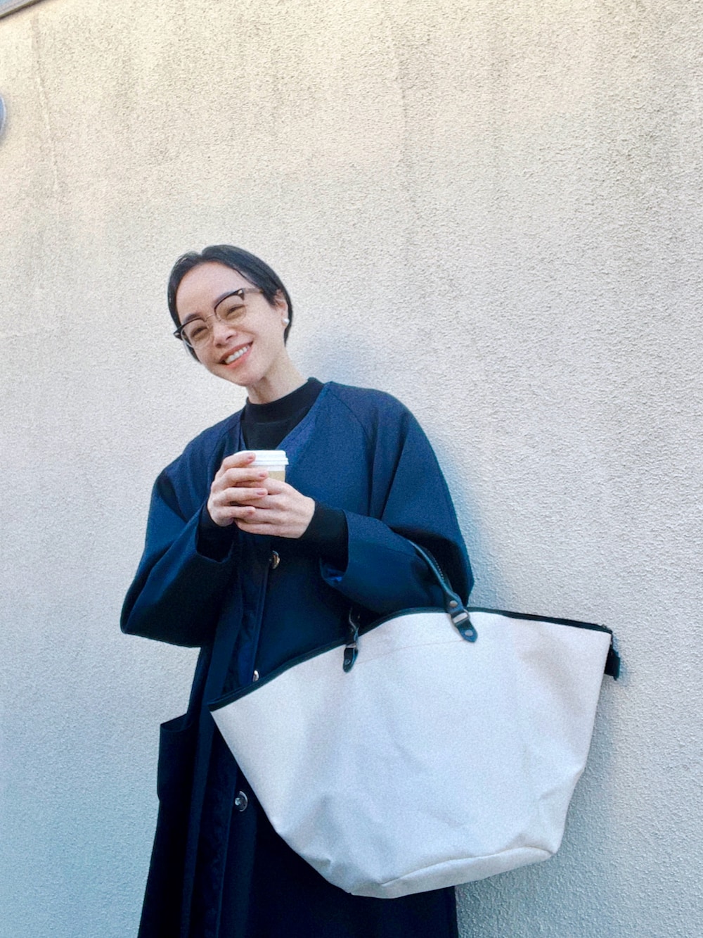 ブルー系のジャケット/アウター、ブラック系のニット/セーター、ホワイト系のバッグを着用したレディースの冬コーディネートの3枚目の写真