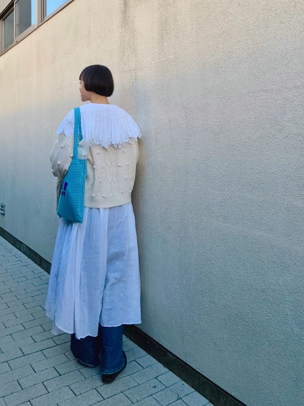 ホワイト系のワンピース、ホワイト系のカーディガン/ボレロ、ブルー系のデニムパンツを着用したレディースの冬コーディネートの2枚目の写真