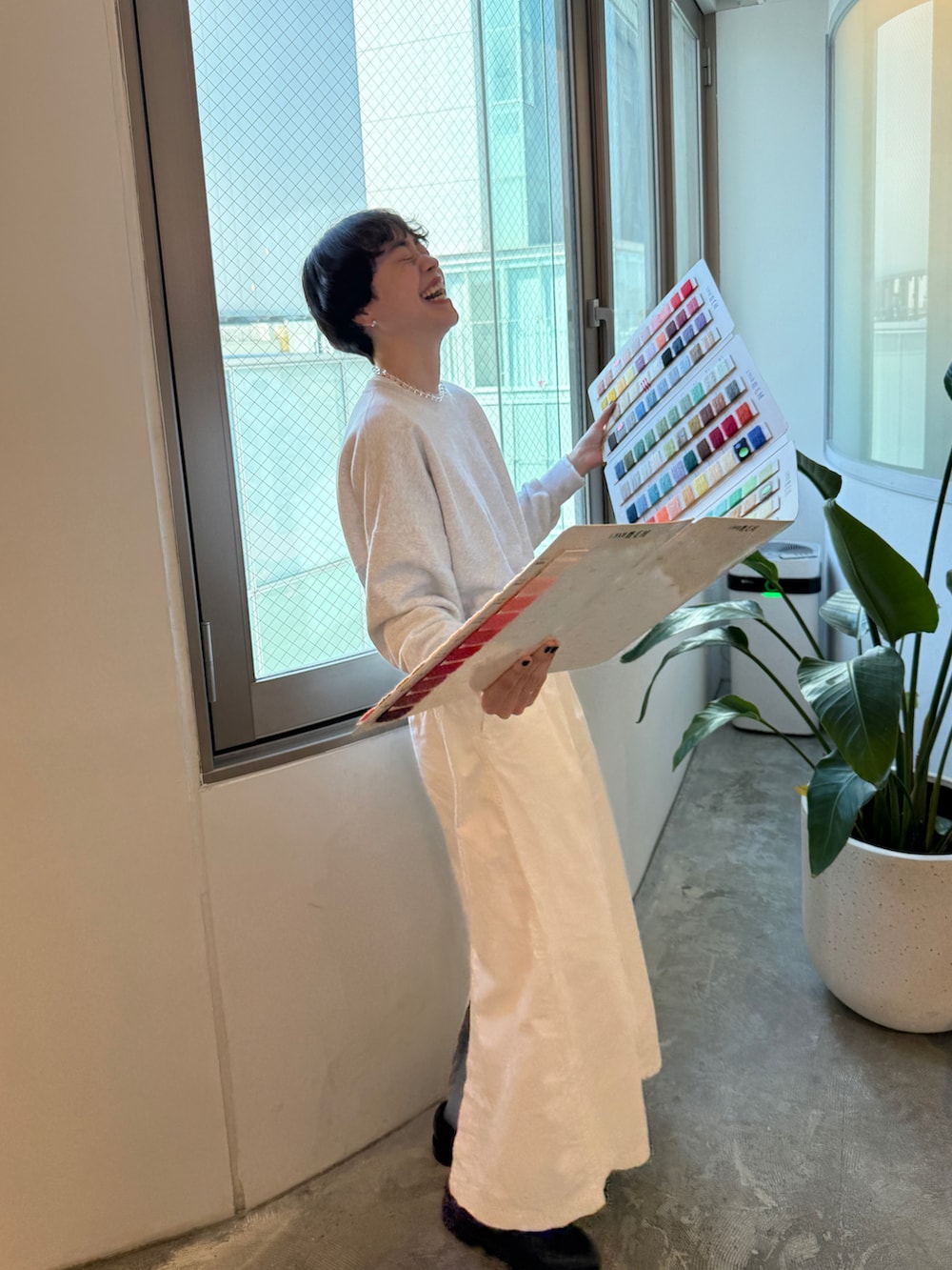 グレー系のスウェット、ホワイト系のスカート、ブラック系のドレスシューズを着用したレディースの春コーディネートの2枚目の写真