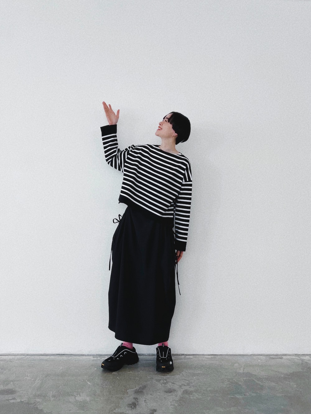 ブラック系のトップス、ブラック系のスカート、ブラック系のシューズを着用したレディースの春コーディネートの2枚目の写真