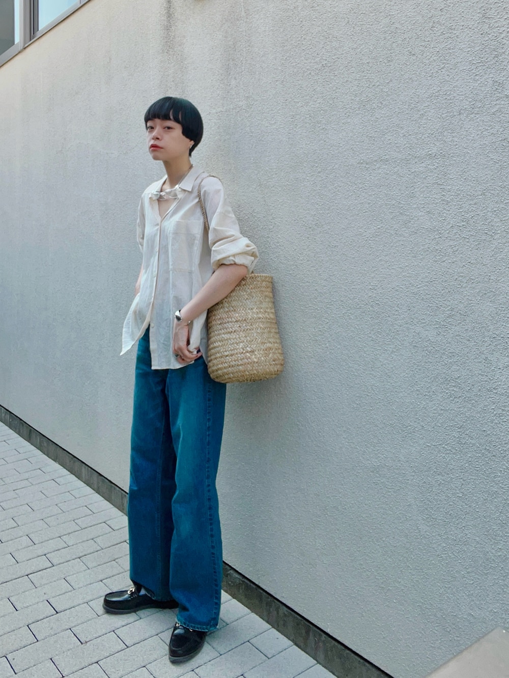 ベージュ系のシャツ/ブラウス、ベージュ系のかごバッグ、ブルー系のデニムパンツを着用したレディースの夏コーディネートの2枚目の写真