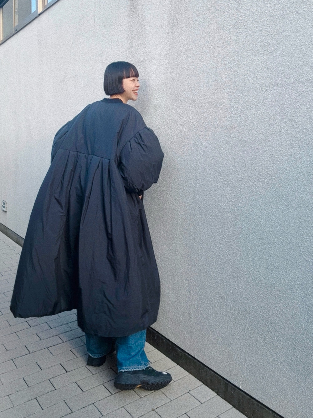 ブラック系のシューズ、ブルー系のデニムパンツ、ブラック系のダウンジャケット/コートを着用したレディースの春コーディネートの2枚目の写真