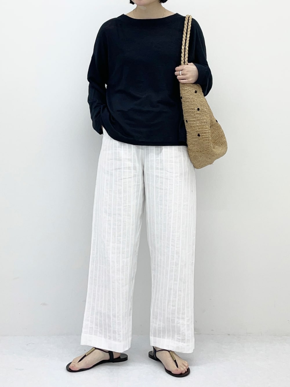 ブラック系のTシャツ/カットソー、ホワイト系のその他パンツ、ベージュ系のバッグを着用したレディースの春コーディネートの4枚目の写真