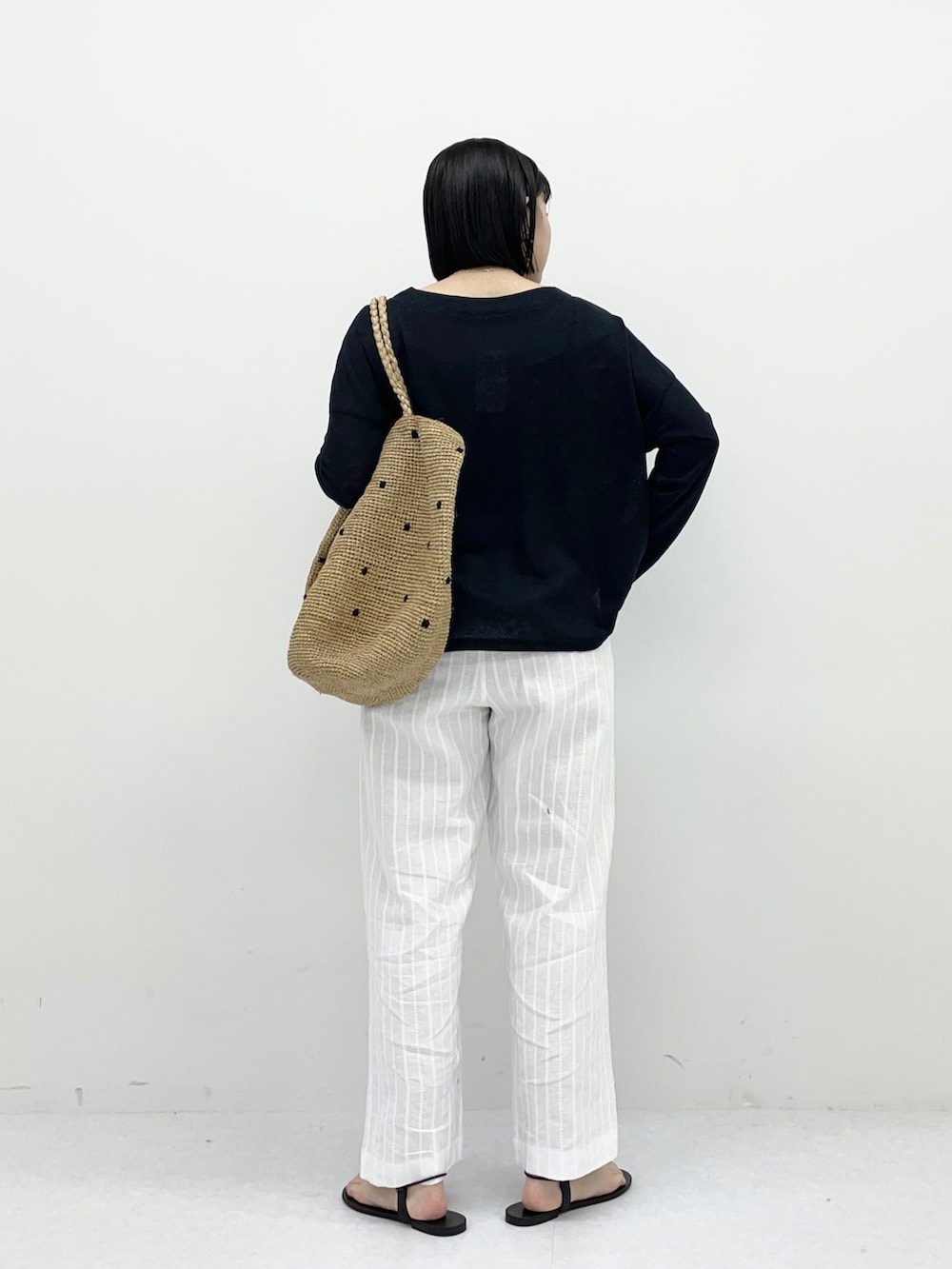 ブラック系のTシャツ/カットソー、ホワイト系のその他パンツ、ベージュ系のバッグを着用したレディースの春コーディネートの3枚目の写真